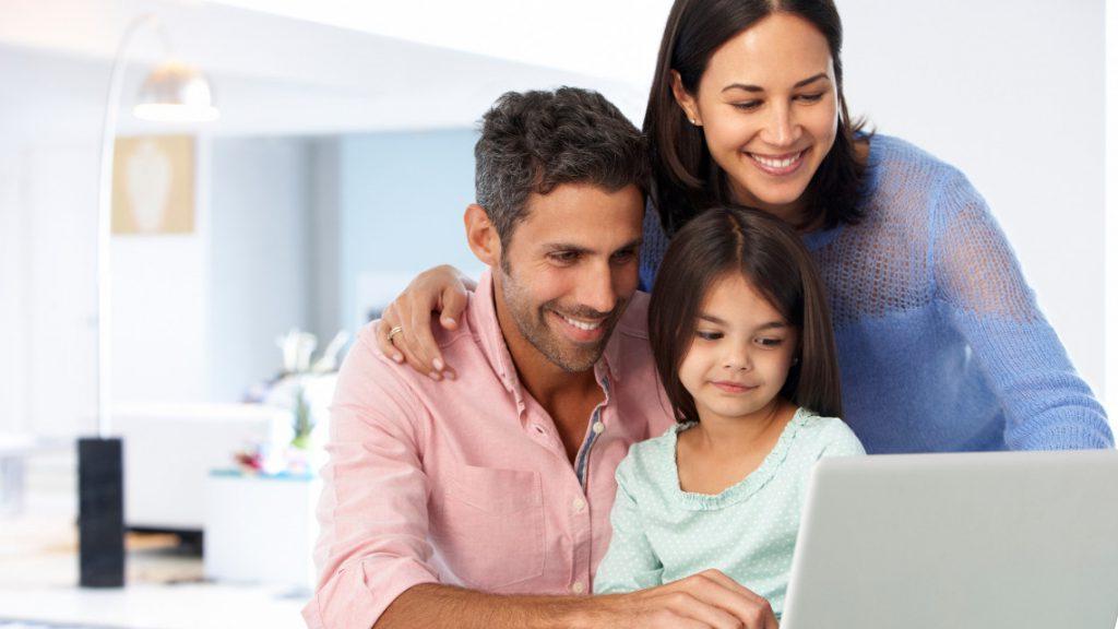Image of a smiling family working together at a laptop